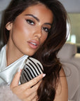 On-the-go lifestyle shot of model using ZIGZAG Travel Hair Brush for effortless styling anywhere.