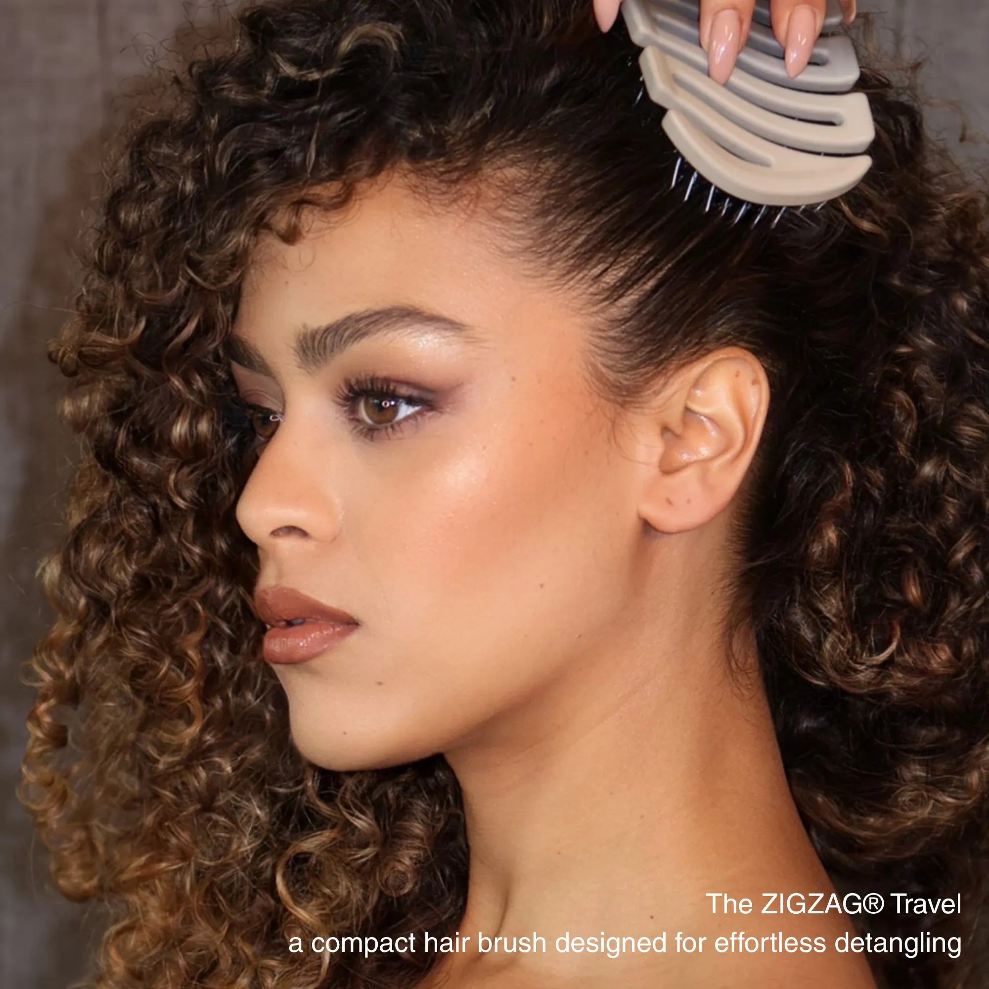 Model detangling curly hair with ZIGZAG Travel Hair Brush for gentle smoothing and scalp massage for healthy hair growth stimulation.